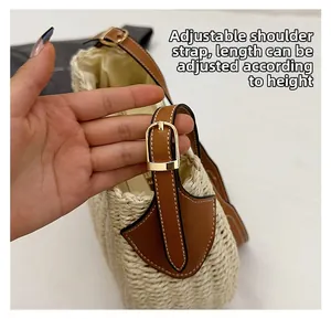 Détail de la bandoulière en cuir marron réglable d'un sac seau en paille tressée