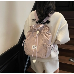 Detail view of the drawstring closure and brand label on a pink water-resistant nylon backpack
