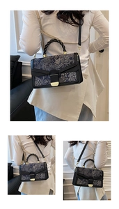 Detail of elegant black leather bag with blue-grey floral embroidery and gold clasp