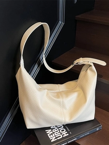 Sac fourre-tout blanc cassé en cuir grainé avec large bandoulière dans un décor élégant