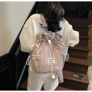 Detail of lavender drawstring backpack with side pockets on model in a stylish urban setting