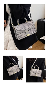 Detail of gray floral embroidery shoulder bag with gold clasp and woven handle