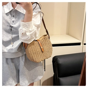 Détail du sac bandoulière en paille avec lanière en cuir marron et boucle métallique