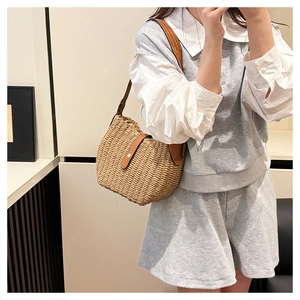 Détail du sac en paille tissé main avec bordure en cuir marron et boucle métallique