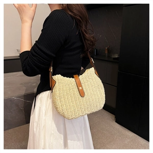 Détail du sac à bandoulière en paille tressée avec lanière en cuir marron et boucle dorée