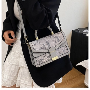 Detail of floral embroidered crossbody bag with woven handle and gold hardware shown on model