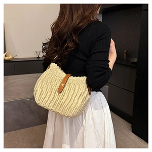 Détail rapproché de la texture tressée du sac seau en paille beige avec cuir