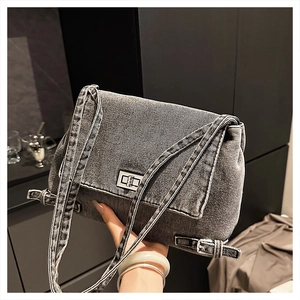 Détail du sac bandoulière en denim gris avec texture vintage et fermoir rotatif argenté