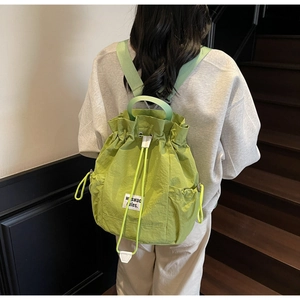 Green drawstring canvas backpack detail view showcasing stylish casual design and strap.