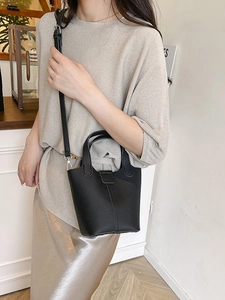 Minimalist black lychee leather bucket bag with top handles and adjustable strap