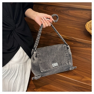 Détail du sac bandoulière en denim vintage avec fermoir rotatif et boucles argentées