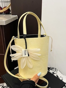 Pale yellow wrinkled leather bucket bag with daisy charm and slim crossbody strap