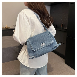 Détail d'un sac cabas en denim bleu avec boucle métallique dans un décor de maison