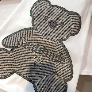 Detailed view of the sparkling rhinestone bear pattern and attitude text on white cotton T-shirt