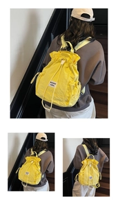 Detail of yellow nylon drawstring backpack showing the adjustable straps and woven label