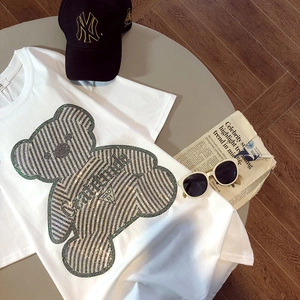 Close-up of white cotton T-shirt featuring a green bear graphic and rhinestone gratitude text