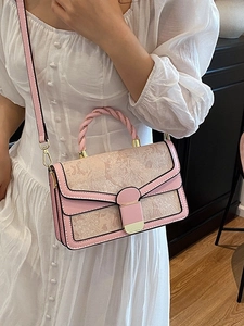 Elegant handbag with butterfly embroidery, woven handle, and gold hardware in home setting