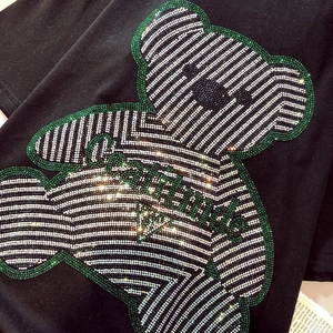 Macro detail of sparkling rhinestone teddy bear design on black cotton T-shirt