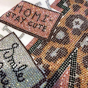 Vue macro détaillée de strass colorés formant un texte sur un T-shirt en coton blanc