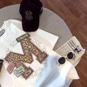 Détail d'un t-shirt blanc en coton avec imprimé léopard M et strass brillants