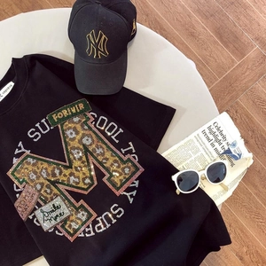 Détail du t-shirt en coton noir avec motif M léopard à paillettes et lettrage style urbain