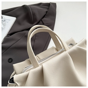 Top view of cream ruched cloud handbag showing lychee leather texture and dual handles