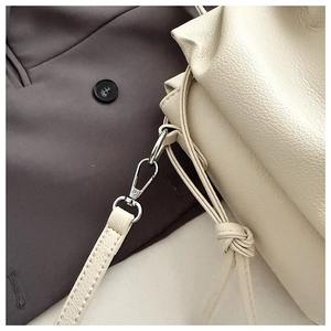 Close-up of cream pleated cloud bag featuring lychee texture and metallic lobster clasp