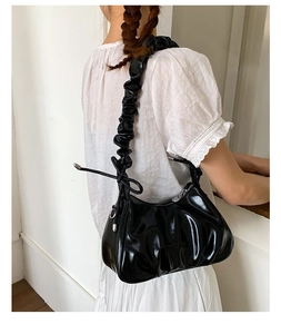 Détail du sac à bandoulière plissé noir brillant avec sangle froncée et liens latéraux