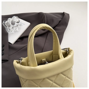 Dettaglio della cucitura a diamante sulla borsa a secchiello color crema in pelle