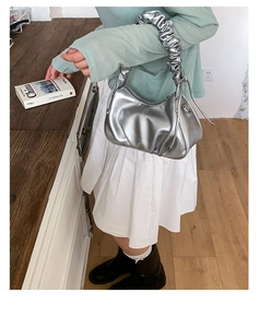 Détail du sac à main argenté métallisé avec poignée froissée et design plissé chic