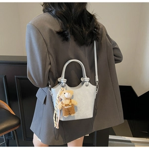 Detail of light blue crocodile texture bag with teddy bear charm and knotted rope handle