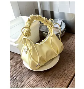 Détail du sac à main froncé jaune clair avec anse plissée et anneaux en métal argenté
