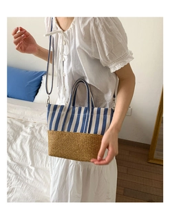 Detail of blue and white striped canvas tote with woven straw base and adjustable strap