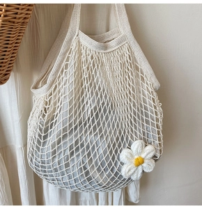 Detail of crochet cotton mesh bag with daisy charm and inner fabric lining pouch