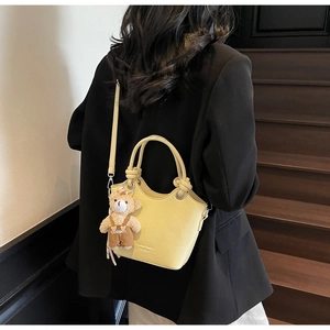 Detail of yellow crocodile embossed bucket bag with knot handle and bear charm