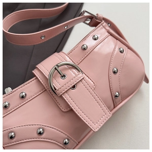 Détail d'un sac baguette en cuir verni rose avec boucles argentées et rivets Y2K