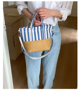 Detail of blue and white striped canvas and woven straw tote bag with shoulder strap