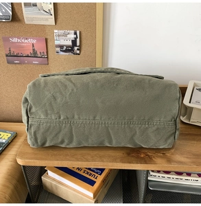 Detailed view of durable olive green canvas fabric and double stitching on the messenger bag