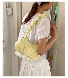 Détail d'un sac à bandoulière plissé jaune pâle en similicuir brillant avec texture