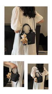 Detail of black crocodile texture bag featuring a cute plush bear pendant and brand logo