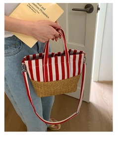 Detail of striped canvas and straw tote bag featuring detachable strap and silver hardware
