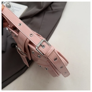 Détail du sac à bandoulière rose brillant avec œillets métalliques et boucles punk
