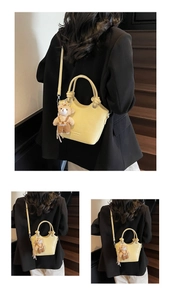 Detail of yellow crocodile embossed tote bag with a cute bear charm on a wooden staircase