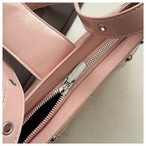 Détail du sac rose avec fermeture éclair argentée, oeillets et rivets décoratifs