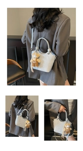 Detail of gray-blue crocodile texture bucket bag with cute teddy bear charm accessory