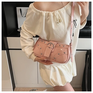 Détail du sac d'épaule en cuir verni rose avec rivets métalliques et boucle de ceinture
