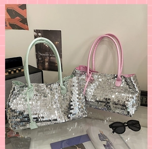 Close-up of sparkling silver sequin tote bags with pink and green straps in retro setting