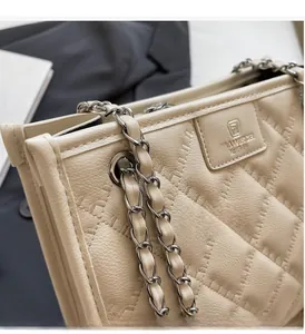 Détail de sac en cuir matelassé beige avec bandoulière chaîne et écusson de logo