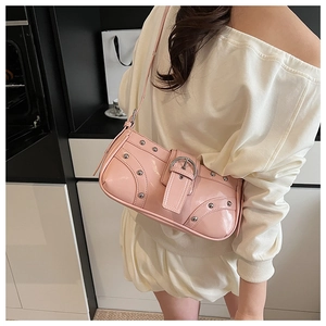 Vue détaillée d'un sac sous le bras en cuir verni rose avec rivets porté par un mannequin