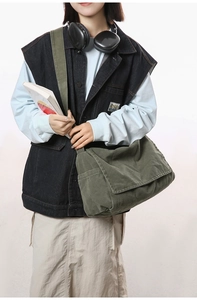 Army green canvas messenger bag worn by a model in a retro Japanese city style look